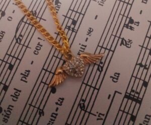 Vista de fragmento de partitura del tema de "Morir por tu amor" decorada con un dije de corazón alado | Fotografia: Efrén Martínez